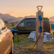 Electric campervan charging from a wooden campsite pillar with a blue CEE cable